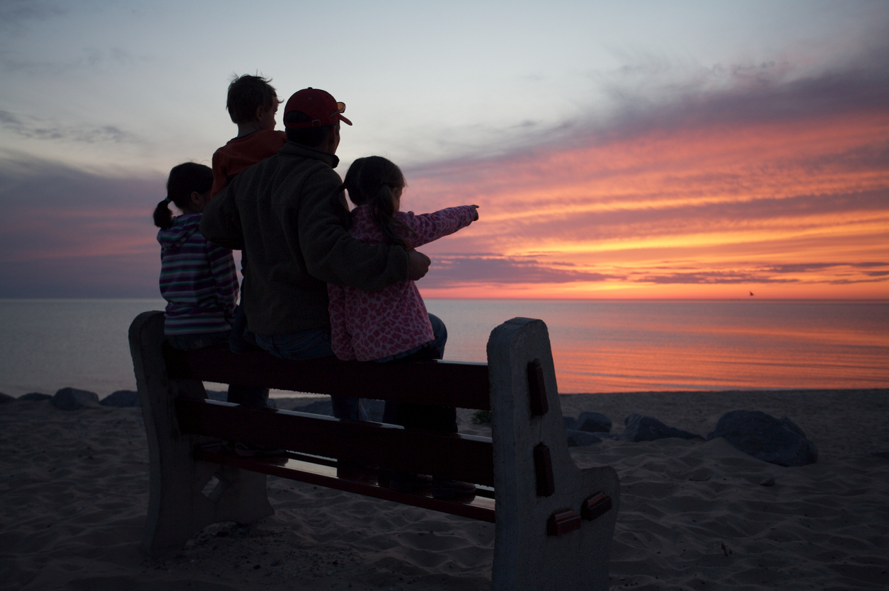 Dad and kids observing a painted sky in the evening on the shores of Sleeping Bear Dunes National Lakeshore. Photo taken in Empire, Michigan.